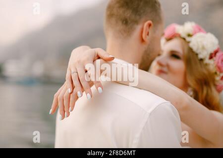 Die Braut und der Bräutigam umarmen sich am Pier, die Braut in einem zarten Kranz wickelte ihre Arme um den Hals des Bräutigams Stockfoto