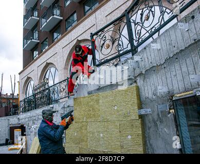 Dnepropetrovsk, Ukraine - 06.04.2021: Ein Mann installiert eine Schicht Wärmedämmung in Form von Mineralwollplatten. Anpassung der Passgenauigkeit. Stockfoto