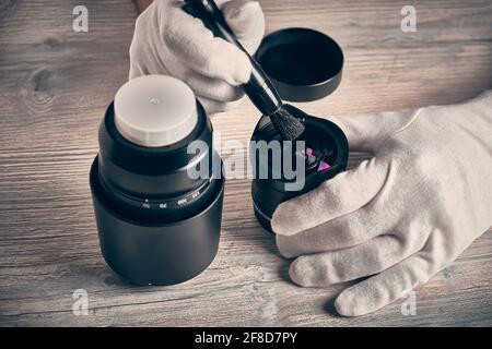 Man reinigt Fotoobjektiv mit Pinsel Stockfoto