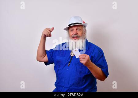 Alter Mann mit weißem Fedora-Hut, blauem Guayabera-Hemd und Bolo-Krawatte, der seine Kreditkarte abweist Stockfoto