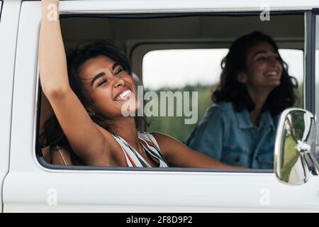 Junge lachende Frau, die ihre Hand aus einem Auto streut Spaß haben Stockfoto