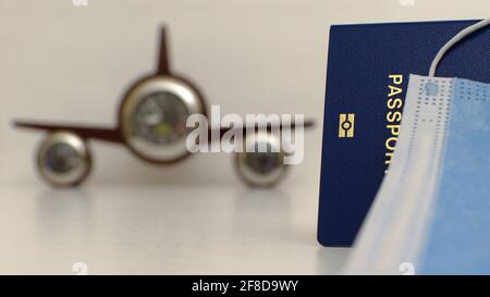 Passport close up auf verschwommenem Hintergrund mit Einweg-Gesichtsmaske und Uhr wie ein Flugzeug, verschwommener Hintergrund Stockfoto