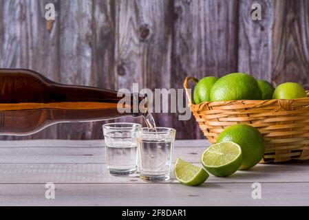 Flasche ausgiessenden Zuckerrohrlikör, ein starkes, typisch brasilianisches alkoholisches Getränk ähnlich Rum, hergestellt in Brasilien aus dem Saft des Zuckerrohrs, in einem s Stockfoto