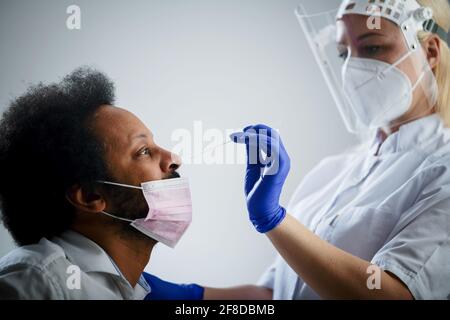 Krankenschwester Herstellung PCR Covid-19 Test für Black man, weißer Hintergrund Stockfoto