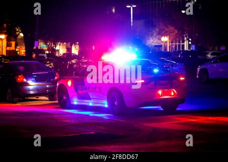 Polizeiauto mit Notbeleuchtung, die in der Nacht in der Stadt aufflackern Von hinten Stockfoto