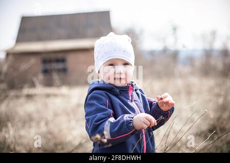 Ein Kind im Hintergrund eines ländlichen verlassenen Hauses. Zerstörte nicht ein Mehrfamilienhaus im Dorf. Wandern in der Natur. Stockfoto