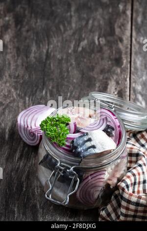 Makrelen in Salzlake mit Zwiebeln und Gewürzen im Glasgefäß Auf Holztisch Stockfoto