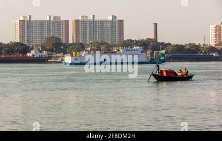 Kalkutta, Westbengalen, Indien - Januar 2018: Ein Boot, das auf dem Wasser des Hooghly-Flusses mit einer Skyline moderner Gebäude in der Stadt Kalkutta segelt Stockfoto