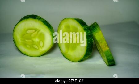 Gurke in Scheiben auf weißem Hintergrund. Salat mit Gurke vorbereiten. Stockfoto