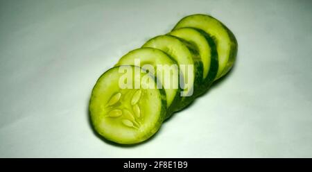 Gurke in Scheiben auf weißem Hintergrund. Salat mit Gurke vorbereiten. Stockfoto