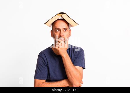 Lustiger Mann mit einem offenen Buch auf dem Kopf denkt und hat Ideen. Stockfoto