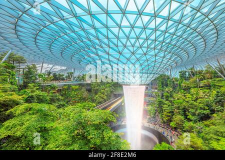 Singapur - 8. Aug 2019: Luftaufnahme von Rain Vortex, dem größten Indoor-Wasserfall der Welt, umgeben von einem vierstöckigen terrassenförmigen Wald und einem Skytrain Stockfoto