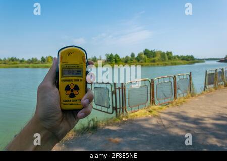 PRIPYAT, UKRAINE, 30. AUGUST 2019: Männliche Hand misst Radioaktivität in der Nähe des Flusses Pripyat in der Ukraine Stockfoto