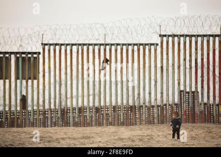 Tijuana, Baja California, Mexiko - 11. April 2021: Ein Kind läuft vor der Grenzmauer der USA, Mexiko. Stockfoto