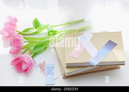 Bücher mit Lesezeichen und Blumen auf hellem Hintergrund Stockfoto