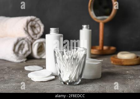 Glas mit Wattestäbchen und Badezubehör auf dem Tisch Badezimmer Stockfoto