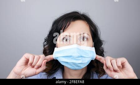 Frau trägt Schutz Gesichtsmaske gegen Coronavirus. Frau zieht Maske weg. Kann nicht atmen. Gesichtsmaske mit den Fingern entfernen. Medizinische Maske, Clos Stockfoto