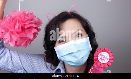 Frau trägt Schutz Gesichtsmaske gegen Coronavirus. Frau in einer Maske mit Party-Versorgung. Alles gute zum Geburtstag Mädchen mit Katze Ohr Stirnband. Medizinische Maske, CL Stockfoto