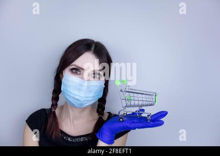 Frau trägt Schutz Gesichtsmaske gegen Coronavirus. Frau in einer Maske und hält den Warenkorb. Medizinische Maske, Nahaufnahme, Fokus wählen, Preventi Stockfoto