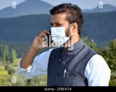 Asian man Tragen Maske ist am Telefon an einem schönen Ort nach Coronavirus Lockdown sprechen. Stockfoto