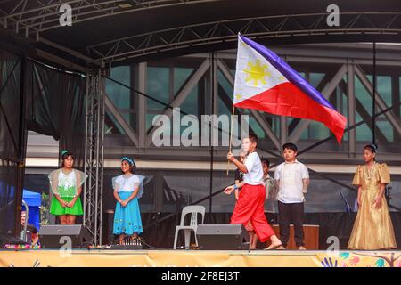 Philippinische Kinder in Nationaltracht tragen die Flagge der Philippinen bei einem multikulturellen Fest. Tauranga, Neuseeland