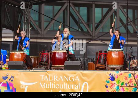 Eine Gruppe von Musikern, die Taiko (traditionelle japanische Holztrommeln) auf der Bühne spielen. Fotografiert auf einem multikulturellen Festival in Tauranga, Neuseeland Stockfoto