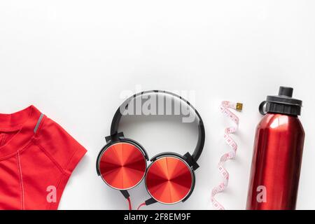 Maßband, Wasserflasche, Kopfhörer und Sportbekleidung auf weißem Hintergrund. Fitness-, Sport- und Trainingskonzept Flat Lay mit Kopierfläche. Stockfoto