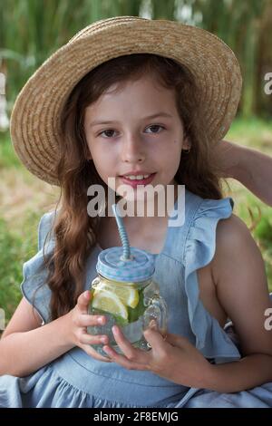Eine junge Dame trinkt Limonade bei einem Picknick in einem parken Sie am Ufer eines Flusses Stockfoto