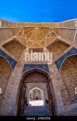 Die Madrasah wurde aus Backstein gebaut und mit drei blauen Kuppeln gekrönt. Die Türen der Zellen (khudjrs) und das Tor von Barak-Khan Madrasah sind mit ivo eingelassen Stockfoto