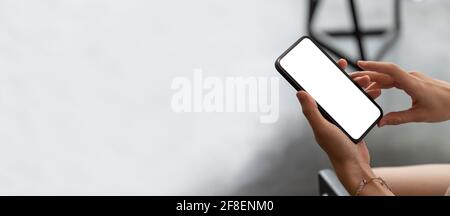 Handy in der Hand einer Frau mit weißem Bildschirm nachgestellt Draufsicht Stockfoto