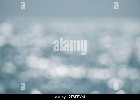 Abstrakte Natur Sommer oder Frühling Meer Meer Hintergrund. Kleine Wellen auf der goldenen, warmen Wasseroberfläche verwischen sich in Bewegung mit Bokeh-Lichtern vom Sonnenuntergang. Urlaub Stockfoto