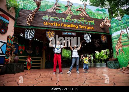 Touristen posieren am Eingangstor der Giraffen-Futterterrasse in der Safari-Welt in Bangkok. Stockfoto