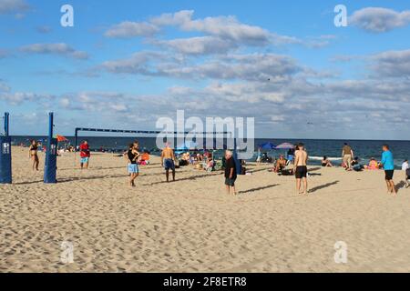 Gruppe von Menschen, die während der COVID-19-Pandemie am Strand von Pompano, Florida, Volleyball spielen. Stockfoto