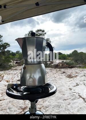 Espresso-Kaffee in einer kubanischen Kaffeemaschine mit einem Mini-Gasherd mit einem Propangasbehälter auf einem einzigen Brenner. Im Hintergrund braut ein Gewitter Stockfoto