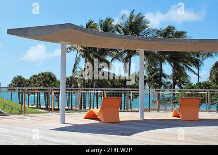 Wunderschöner Loungebereich im Freien mit orangefarbenen Strandliegen unter Schatten. Tropisches Paradies Hotelurlaub in Miami Beach, Florida. Stockfoto