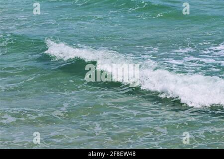 Türkisgrünes Meerwasser. Klares Meerwasser mit Meeresschaum in einer kleinen Welle. Copyspace, Hintergrundbild, Hintergrund Stockfoto