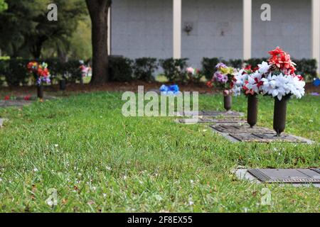 Blumenstrauß, der auf einer Friedhofstafel eines geliebten Verlorenen liegt. Friedhof, Verlust eines geliebten Konzepts. Stockfoto