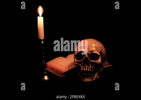 Ein Totenkopf, ein Buch und eine Kerze Stockfoto