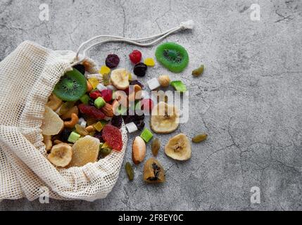 Verschiedene getrocknete Früchte und Nüsse in einem Öko-Beutel auf Ein grauer Betonhintergrund Stockfoto