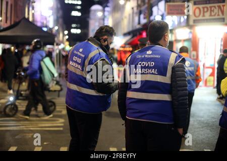 London, England, Großbritannien. April 2021. Westminster Covid Marshalls beobachten die Menge der Nachtschwärmer auf der Old Compton Street, wie die Nacht in Londons Soho am zweiten Tag der Lockerung der Coronavirus-Sperre schließt. Kredit: Tayfun Salci/ZUMA Wire/Alamy Live Nachrichten Stockfoto