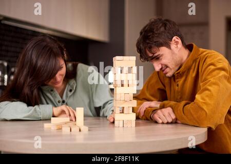 Paar spielen Jenga auf dem Tisch, während sie im Wohnzimmer sitzen. Familie viel Spaß zu Hause Stockfoto
