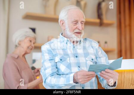 Grauhaariger bärtiger Mann, der etwas liest und dabei aussieht Stockfoto