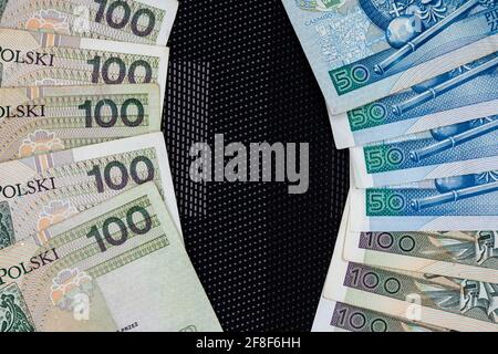 Polnische Banknoten von 100 PLN und 50 PLN auf schwarzem Hintergrund. Foto aufgenommen unter weichem Kunstlicht Stockfoto