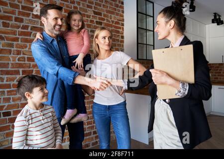 Familie schüttelt die Hände mit Immobilienmakler in neuen Wohnungen Stockfoto