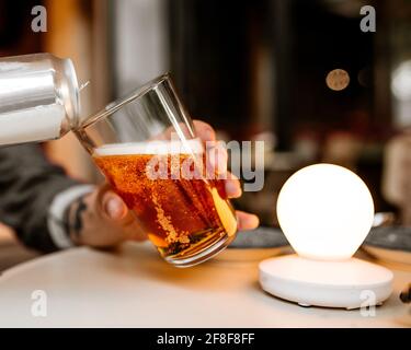 Gießen Sie frisches Bier aus einer Dose ins Glas Stockfoto