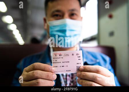 (210414) -- CHANGSHA, 14. April 2021 (Xinhua) -- EIN Passagier legt sein Ticket zum Preis von 1 Yuan im Zug 7266 in der zentralchinesischen Provinz Hunan vor, 11. April 2021. Die 7265/7266/7267-Züge wurden 1995 in Betrieb genommen und erstrecken sich über mehr als 300 Kilometer vom Bahnhof Huaihua zum Bahnhof Lixian. Die Züge fahren in 9 Stunden und 16 Minuten an 37 Haltestellen vorbei. Die Ticketpreise reichen von 1 Yuan bis 23.5 Yuan (etwa 0.15-3.59 US-Dollar), die seit 26 Jahren nicht mehr angehoben wurden. Die Züge fahren durch die Wuling Mountains. Dank ihnen können Dorfbewohner nicht nur Obst, Gemüse und tragen Stockfoto