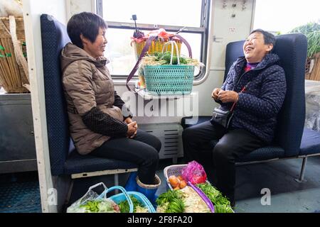 (210414) -- CHANGSHA, 14. April 2021 (Xinhua) -- Passagiere unterhalten sich im Zug 7266 in der zentralchinesischen Provinz Hunan, 11. April 2021. Die 7265/7266/7267-Züge wurden 1995 in Betrieb genommen und erstrecken sich über mehr als 300 Kilometer vom Bahnhof Huaihua zum Bahnhof Lixian. Die Züge fahren in 9 Stunden und 16 Minuten an 37 Haltestellen vorbei. Die Ticketpreise reichen von 1 Yuan bis 23.5 Yuan (etwa 0.15-3.59 US-Dollar), die seit 26 Jahren nicht mehr angehoben wurden. Die Züge fahren durch die Wuling Mountains. Dank ihnen können die Dorfbewohner nicht nur Obst, Gemüse und andere lokale Produkte mitnehmen Stockfoto