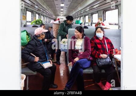 (210414) -- CHANGSHA, 14. April 2021 (Xinhua) -- Passagiere sprechen im Zug 7266 in der zentralchinesischen Provinz Hunan, 11. April 2021. Die 7265/7266/7267-Züge wurden 1995 in Betrieb genommen und erstrecken sich über mehr als 300 Kilometer vom Bahnhof Huaihua zum Bahnhof Lixian. Die Züge fahren in 9 Stunden und 16 Minuten an 37 Haltestellen vorbei. Die Ticketpreise reichen von 1 Yuan bis 23.5 Yuan (etwa 0.15-3.59 US-Dollar), die seit 26 Jahren nicht mehr angehoben wurden. Die Züge fahren durch die Wuling Mountains. Dank ihnen können die Dorfbewohner nicht nur Obst, Gemüse und andere lokale Produkte mitnehmen Stockfoto