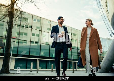 Gemischte Rennkollegen gehen zusammen, um während der Arbeit elegant gekleidet zu arbeiten Diskussion von Projektideen Stockfoto