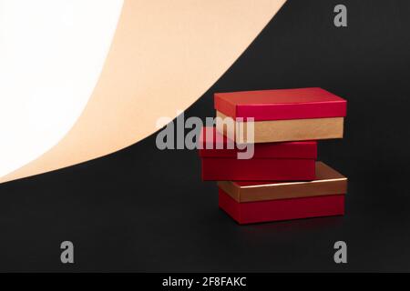 Ein Turm aus drei goldroten Kästchen auf einem Hintergrund aus beigem, schwarzem und weißem Papier Stockfoto